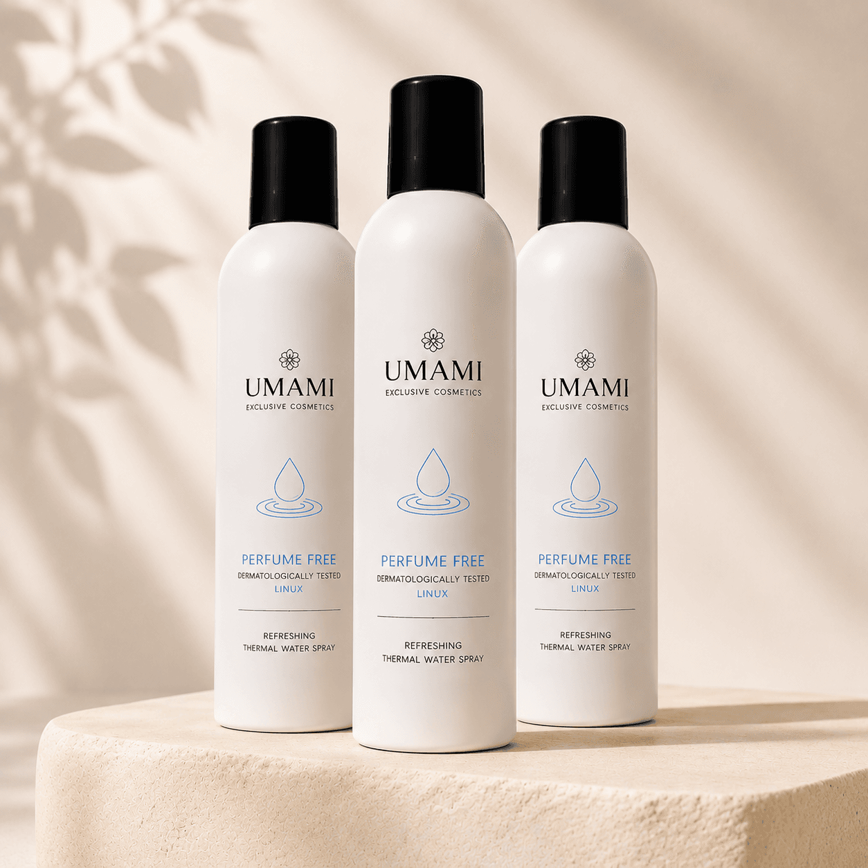 UMAMI Exclusive Cosmetics Thermal Water Spray trio 3x 300ml, witte spuitbussen met zwarte dop op zandstenen podium